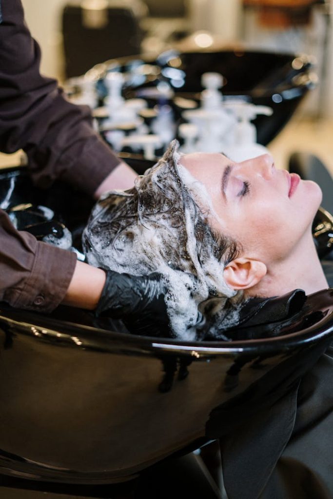 person-washing-woman-s-hair-3993449 Professional hair stylist washing womans hair in a modern salon setting.